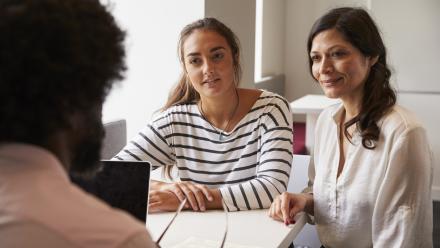 Mom and adolescent daughter meeting with a male teacher