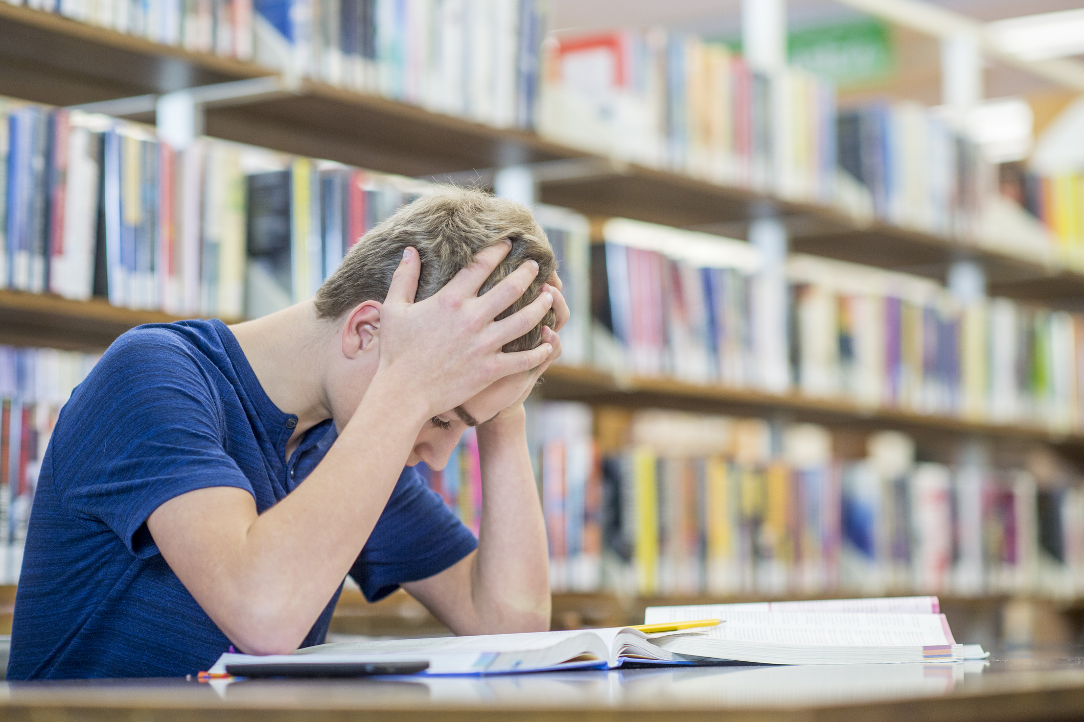 Bly with hands in his hair looking dejectedly at a book in the library