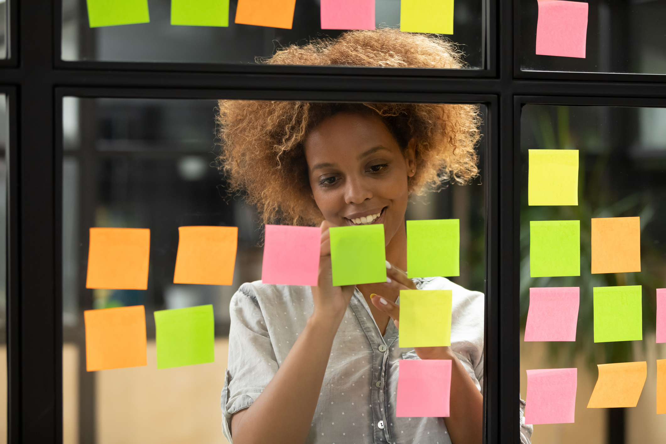 Teacher writing on sticky notes posted on a class wall