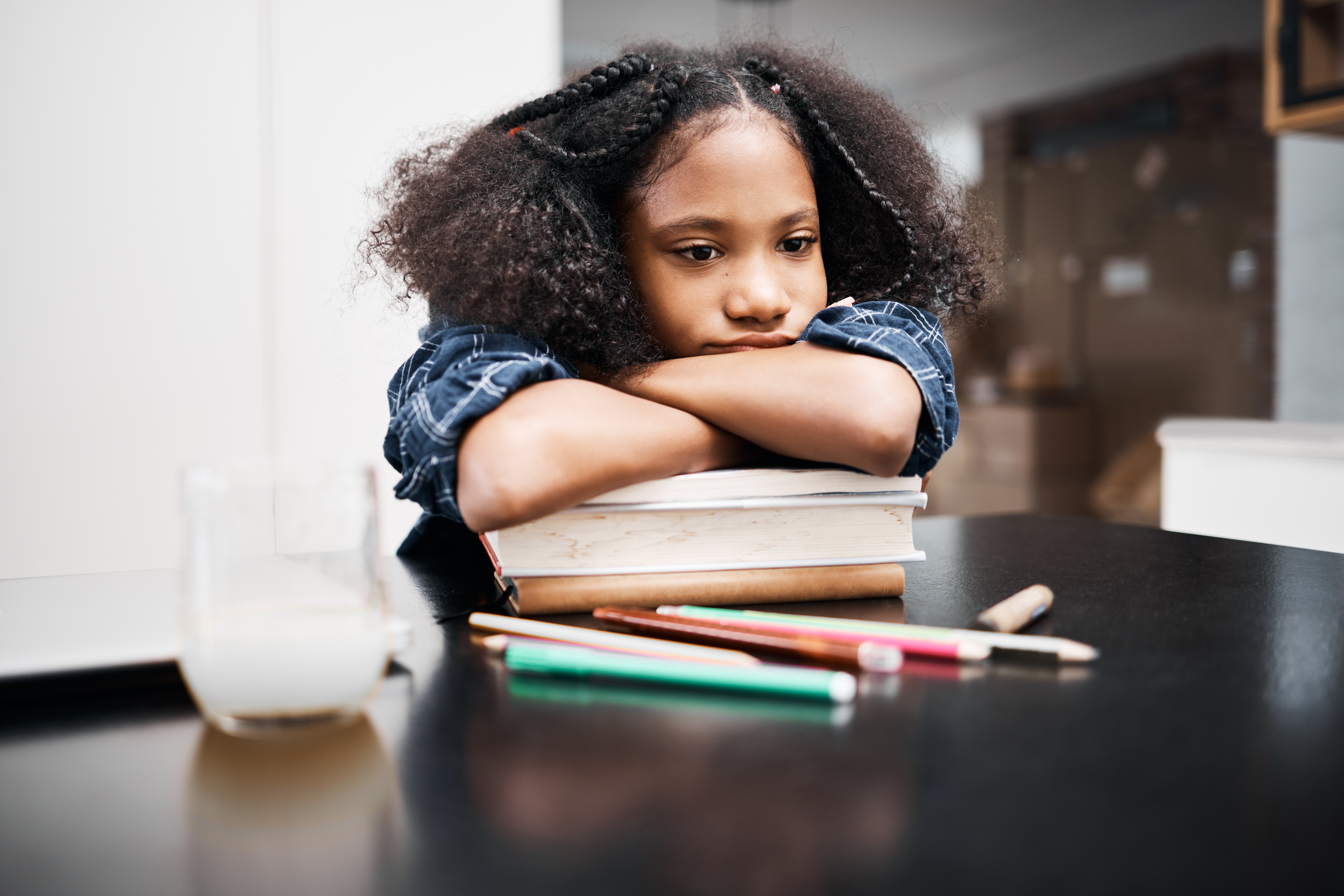 girl with her arms crossed, resting her chin over a stack of school books