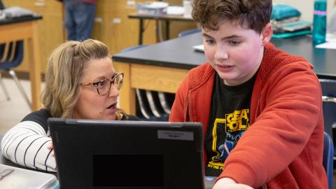 Middle school teacher working one-on-one with student at computer