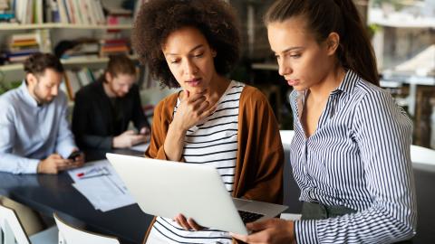 Black female teacher and mixed race female colleague talking at a small group professional development session
