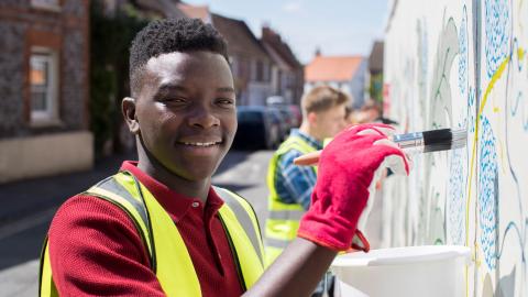 Black teen painting city mural for service project