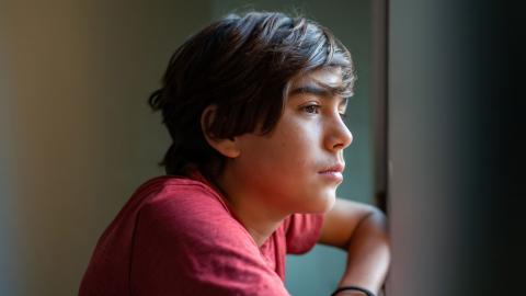 Young teen boy looking pensively out the window