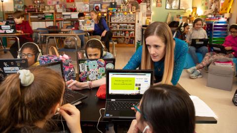 Multicultural middle school class working independently with laptop and teacher coaches