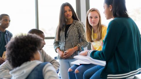 Multicultural group of teens talking about a book