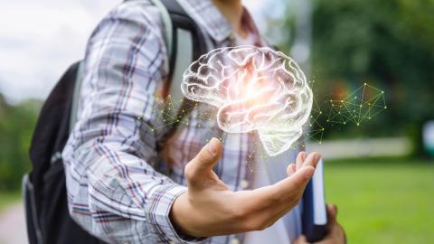 adolescent boy walking with his backpack on and an image of a brain in his hand
