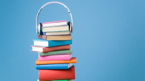 Stack of colorful books with a headset resting on the top of the stack