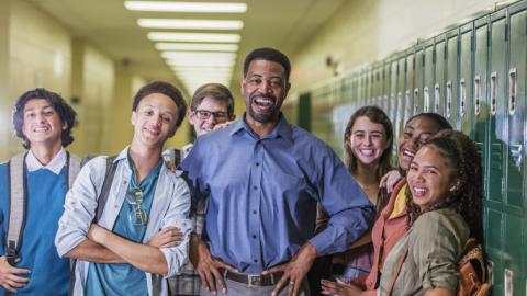 Principal surrounded by smiling high school students