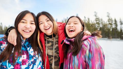 Group of three indigenous teen girls smiling into the camera