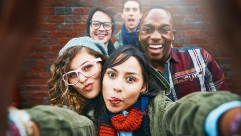 Group of five teens making silly faces and smiling into the camera