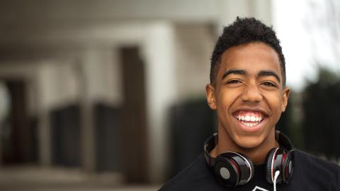Teen boy listening to music and smiling at the camera
