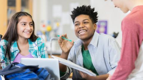 three middle school aged students laughing with one another