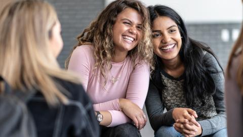 Two teen girls leaning into one another and smiling.