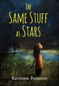 A young girl standing in a field looking up at the stars.