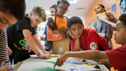Multicultural group of middle school kids in class discussing project