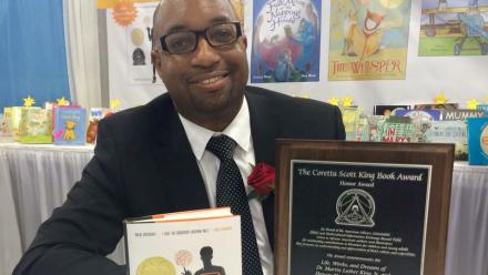 Children's and YA author Kwame Alexander holding his book The Crossover with Coretta Scott King Award