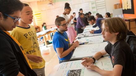 Multicultural group of middle school students sharing project based learning