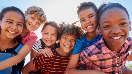 Group of six multicultural middle school kids outdoors smiling 