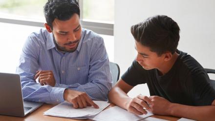 Male Latino teacher discussing assessment results with male Latino student