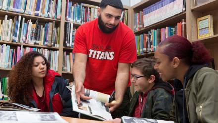 Male volunteer working with multicultural youth at community literacy center