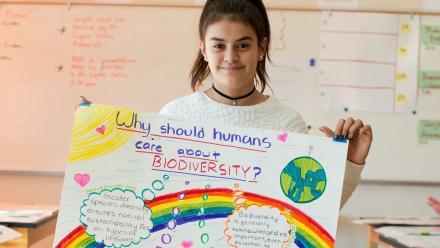 Latina middle school student holding up her poster on biodiversity