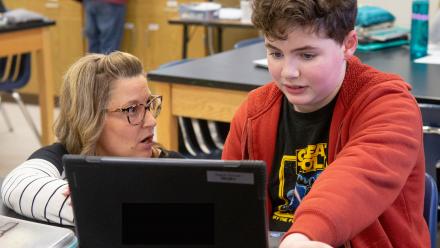 Middle school teacher working one-on-one with student at computer