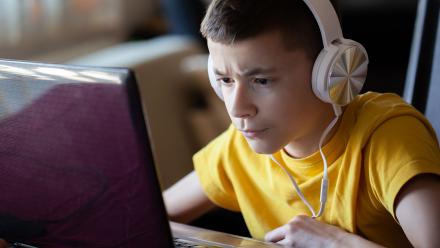 Male high school student using headphones for class lesson