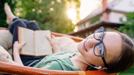 Teen girl reading and listening to audiobook outside