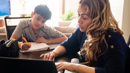 Latina mother supporting middle school son's academic work at home 