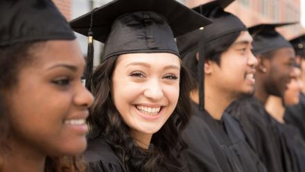 Multicultural group of high school graduates in cap and gown