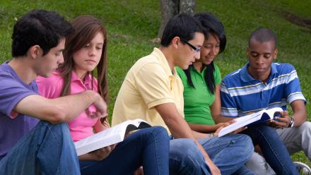 Multicultural group of high school students outside discussing class reading