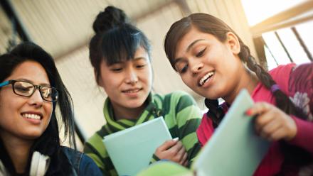 Three high school ELL students looking at book