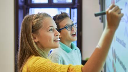 Two middle school students working at white board
