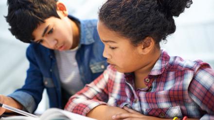 two middle school students reading a class text together