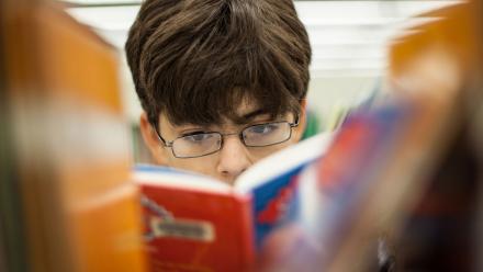 Middle school boy looking at graphic novel in the library