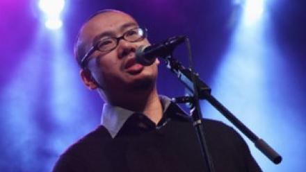 Bao Phi in a night club at the microphone speaking