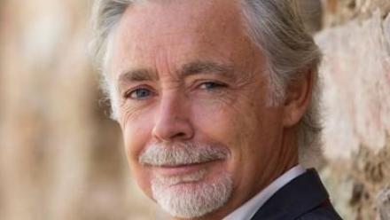 Headshot of Eoin Colfer leaning against a brick wall.