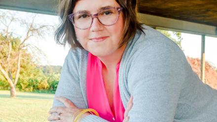Woman leaning on a railing, smiling into the camera