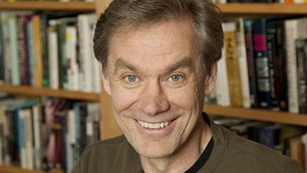 Headshot of John Coy in front of bookcase