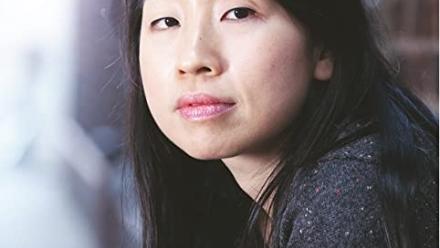 Elsie stares into the camera while leaning against a brick wall.