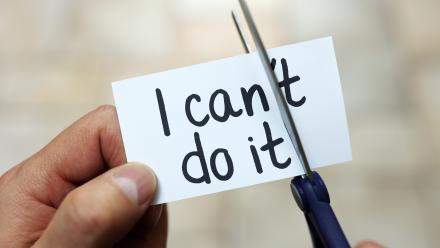 Child cutting up a "I can't do it" card to read "I can do it"