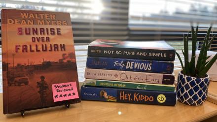 five YA books on display in the classroom with a sticky note on one cover