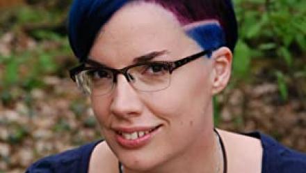 Head shot of Marieke Nijkamp wearing blue rimmed glasses and bright, blue hair