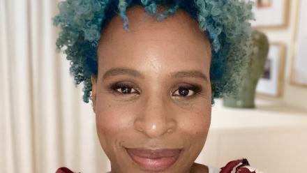 picture of the author with blue hair and wearing a burgandy and white dress.