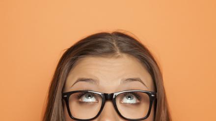 Half portrait of a young girl with glasses looking up stock photo 