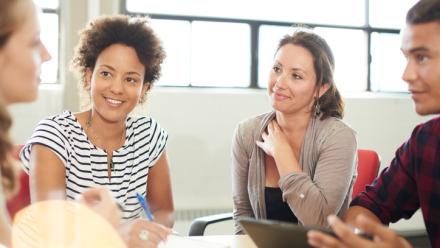 Teachers at a round table in discussion with one another