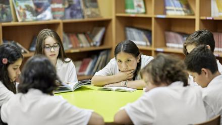 Early adolescents sitting at round table and reading their books.