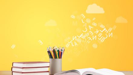 books on a table with pencils and letters scrawled across a yellow wall