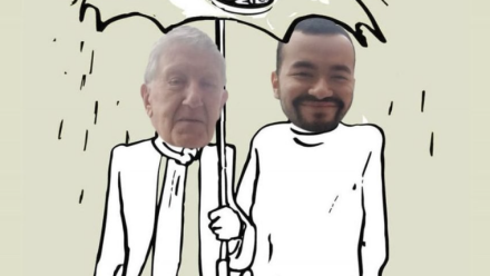 Older and younger men standing under an umbrella as it rains.